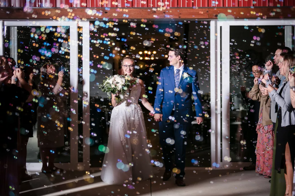bride & groom surrounded by colorful bubbles as they exit their reception