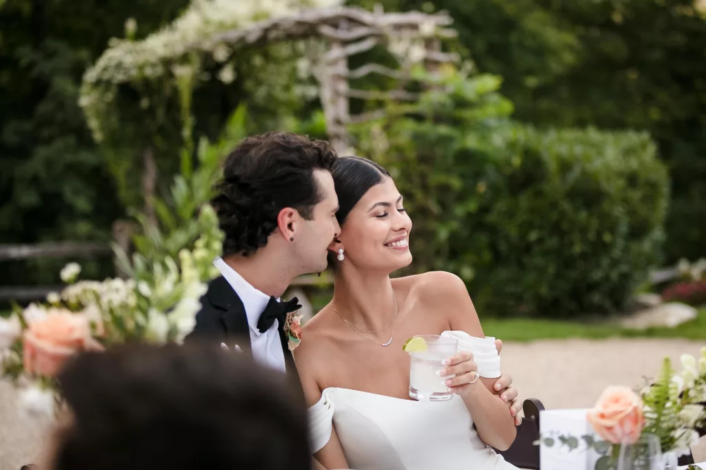 Bride & groom toasting during speeches. Set in a beautiful green garden.