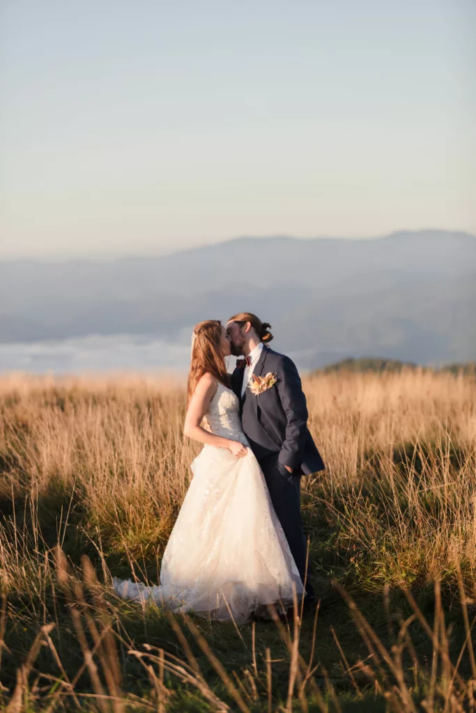 bride & groom kissing with mountains behind them and the clouds rolling in